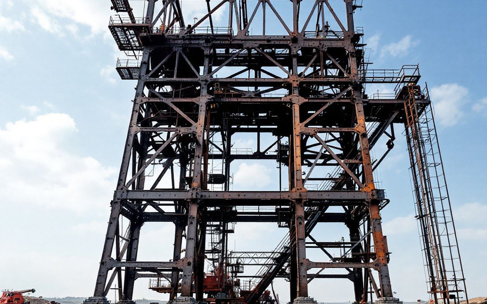 A mine headframe of riveted steel standing against a flat sky